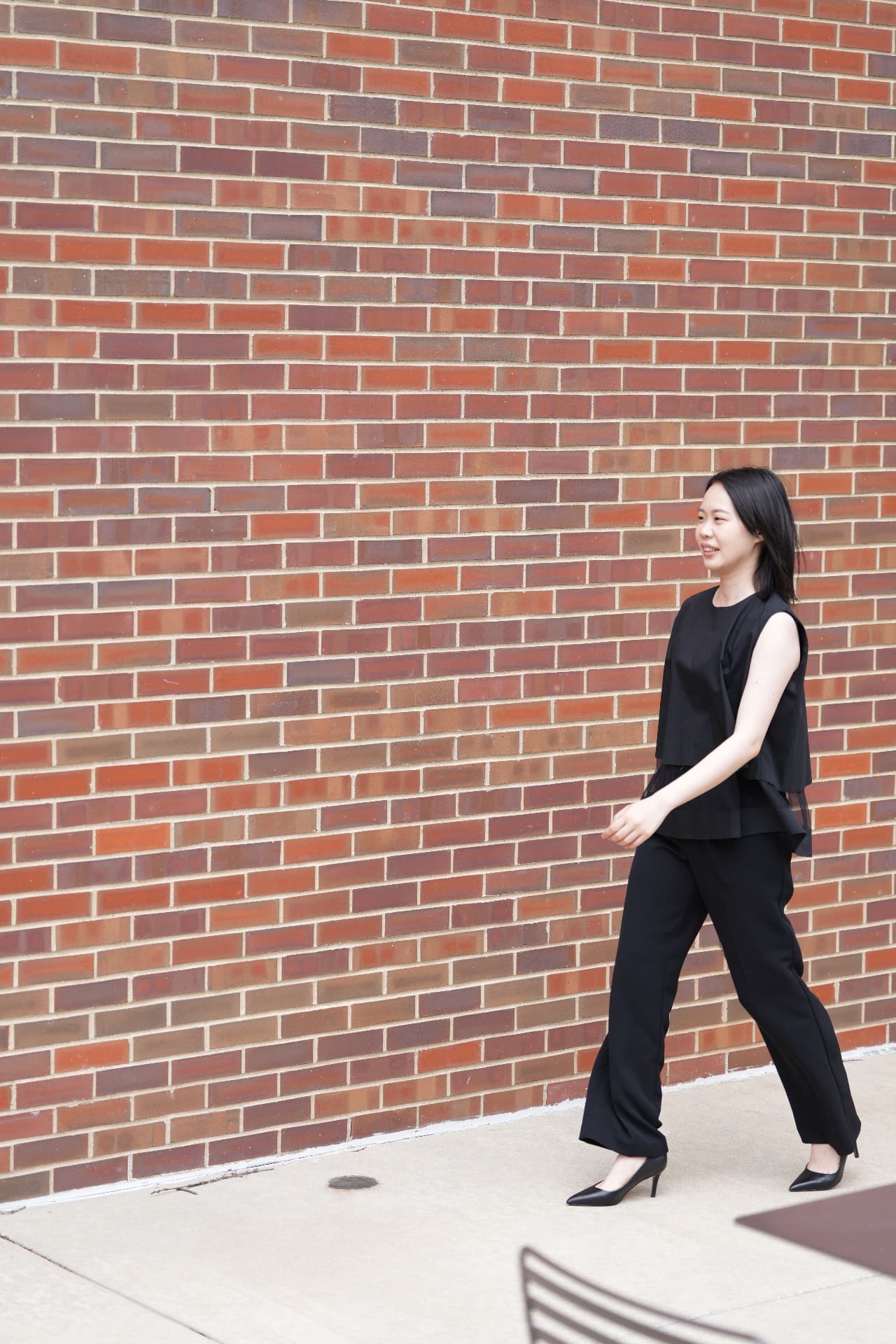 Yi-Hui Chen walking past a color brick wall in black concert attire
