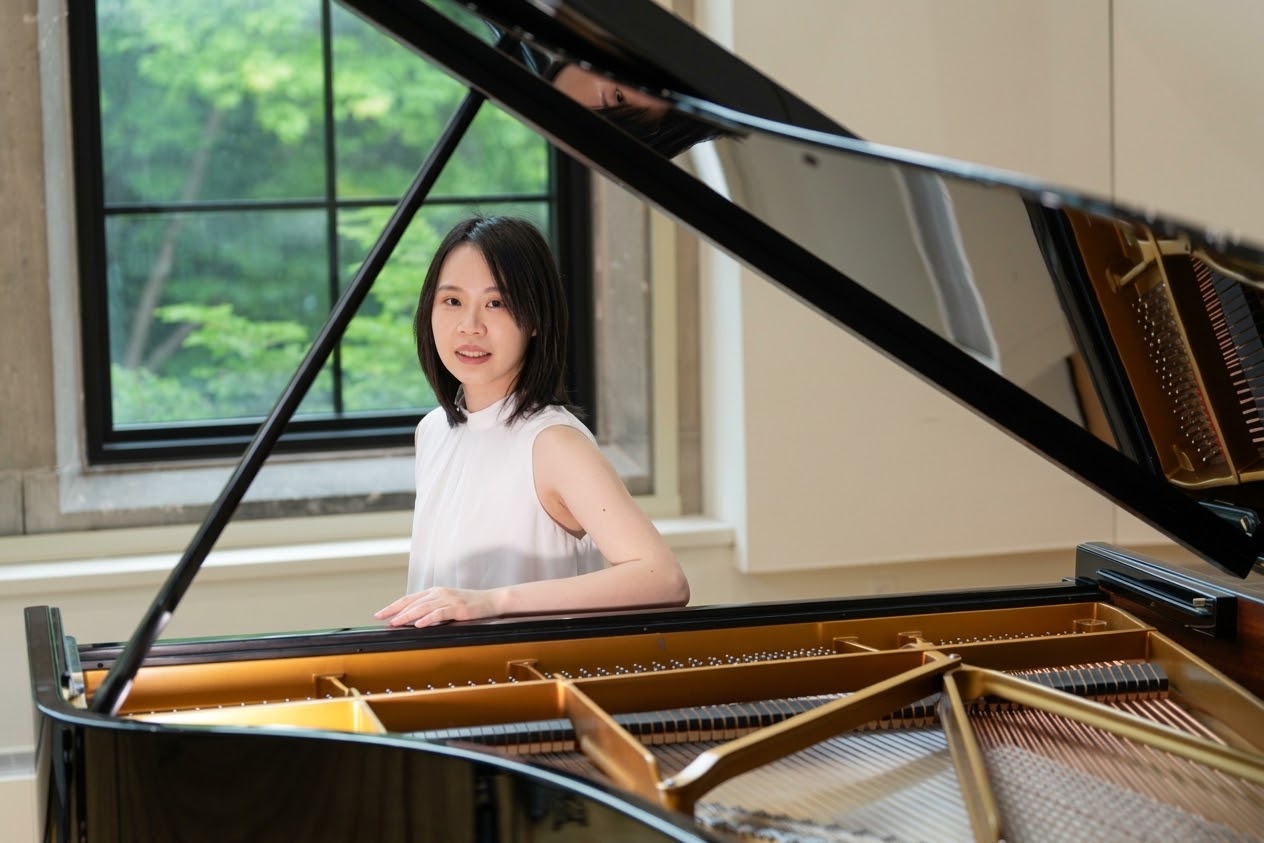 Yi-Hui Chen seated at a grand piano beside a window